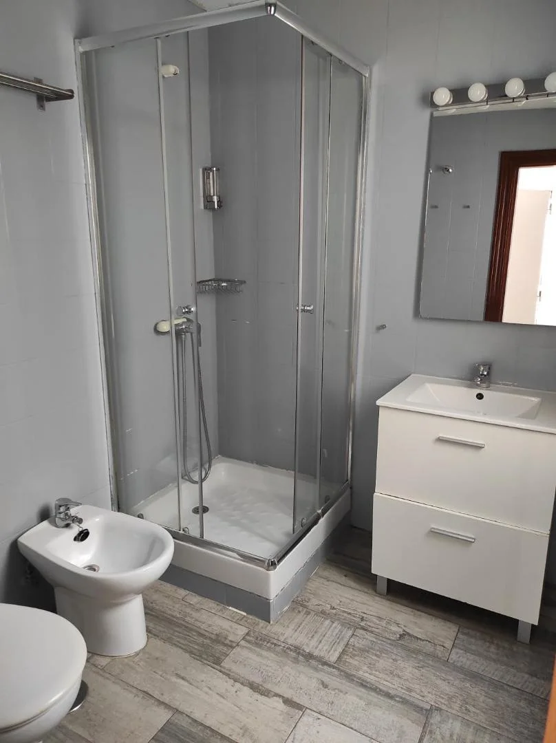 Baño con ducha de cristal y lavabo con mueble