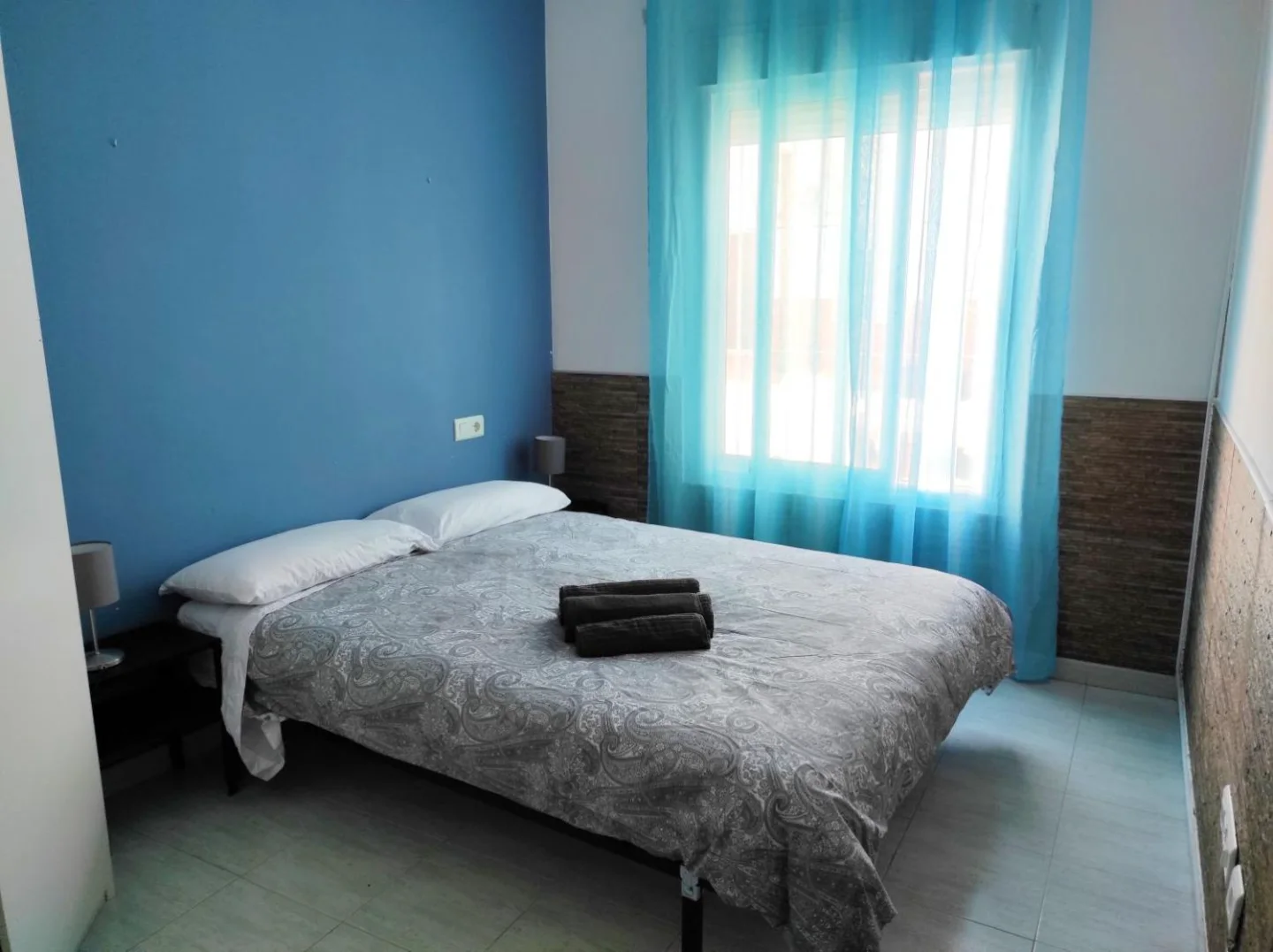 Dormitorio con pared azul y cortinas turquesa