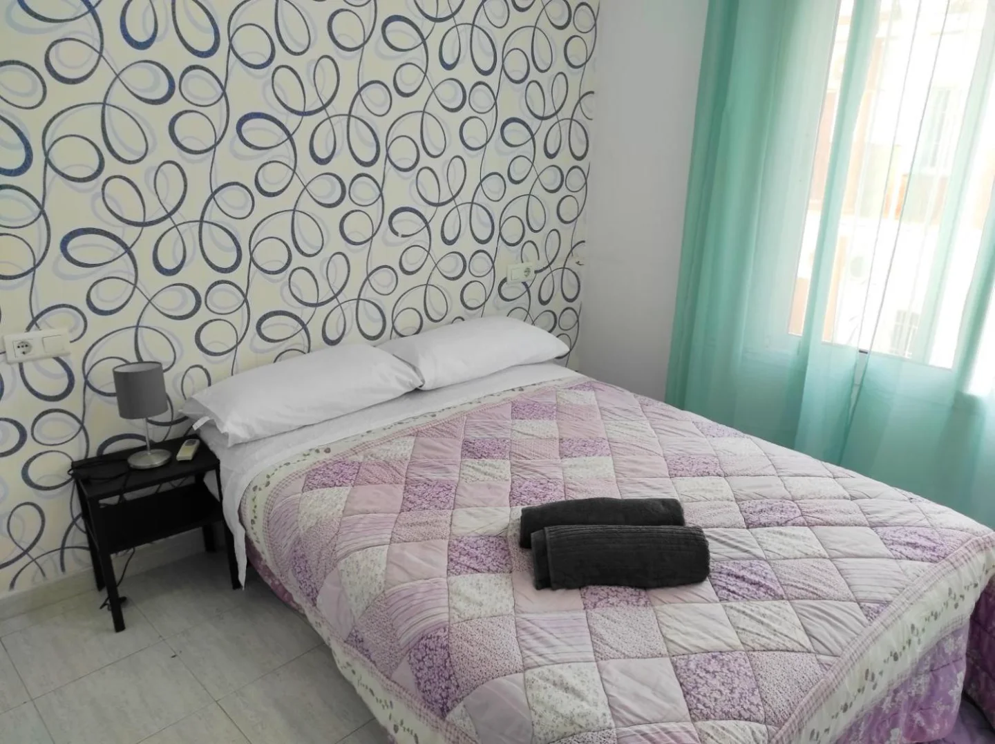 Dormitorio con colcha lila y cortina verde agua