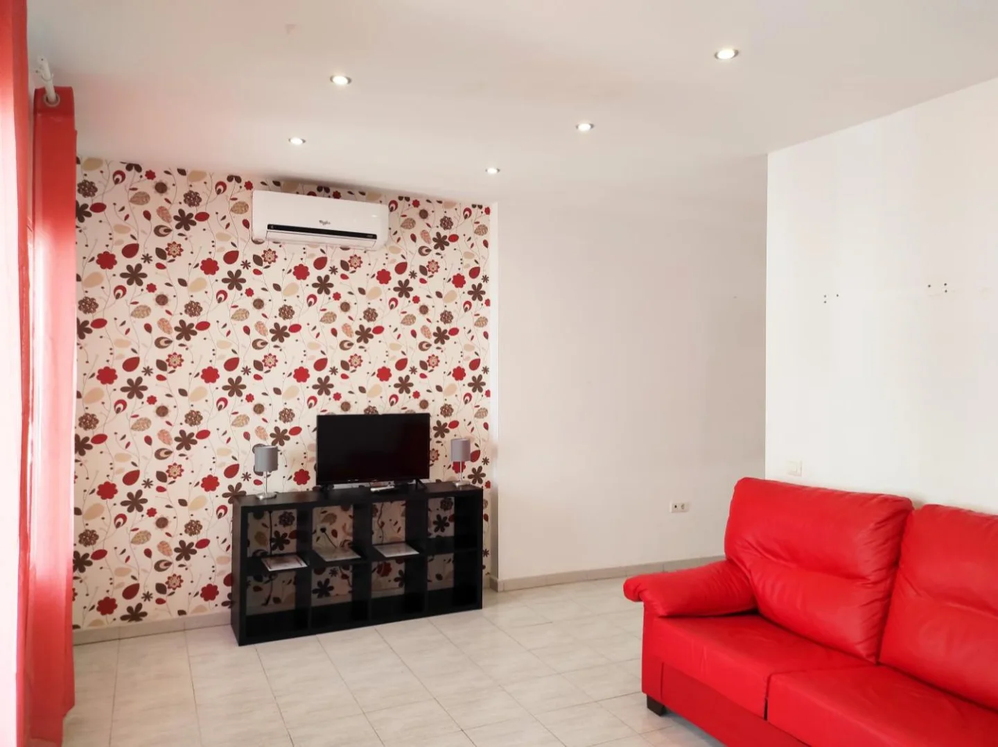 Salón con sofá rojo y pared de flores